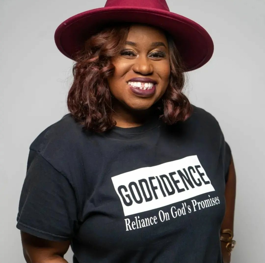 Ashley Kennedy smiling in a burgundy hat and Godfidence shirt